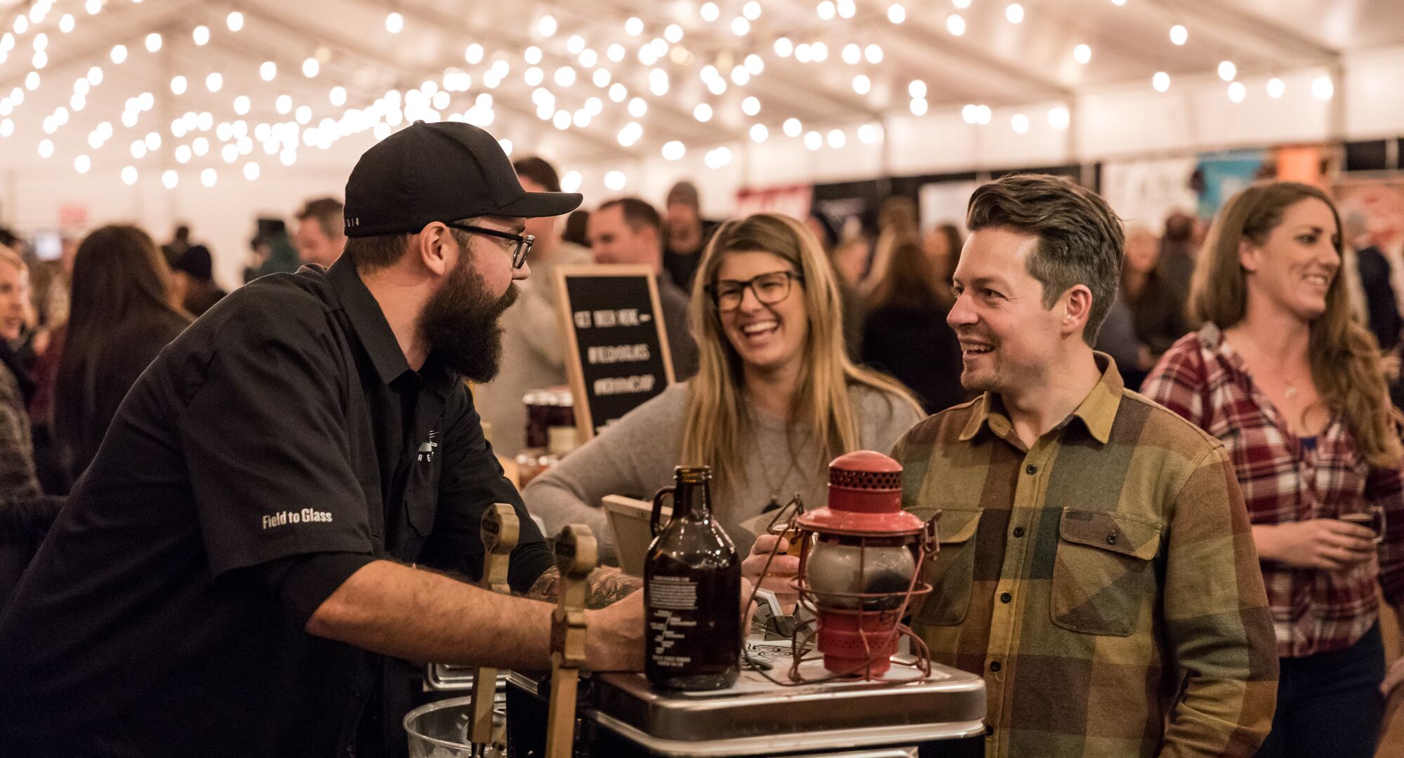 Two people conversing with a Craft Beer vendor at the Banff Craft beer Festival.