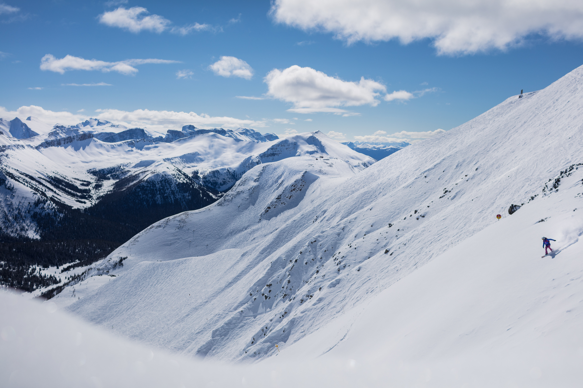 An aerial view of a snowboarder going down the massive mountain while snowboarding at Lake Louise Ski Resort in Banff National Park