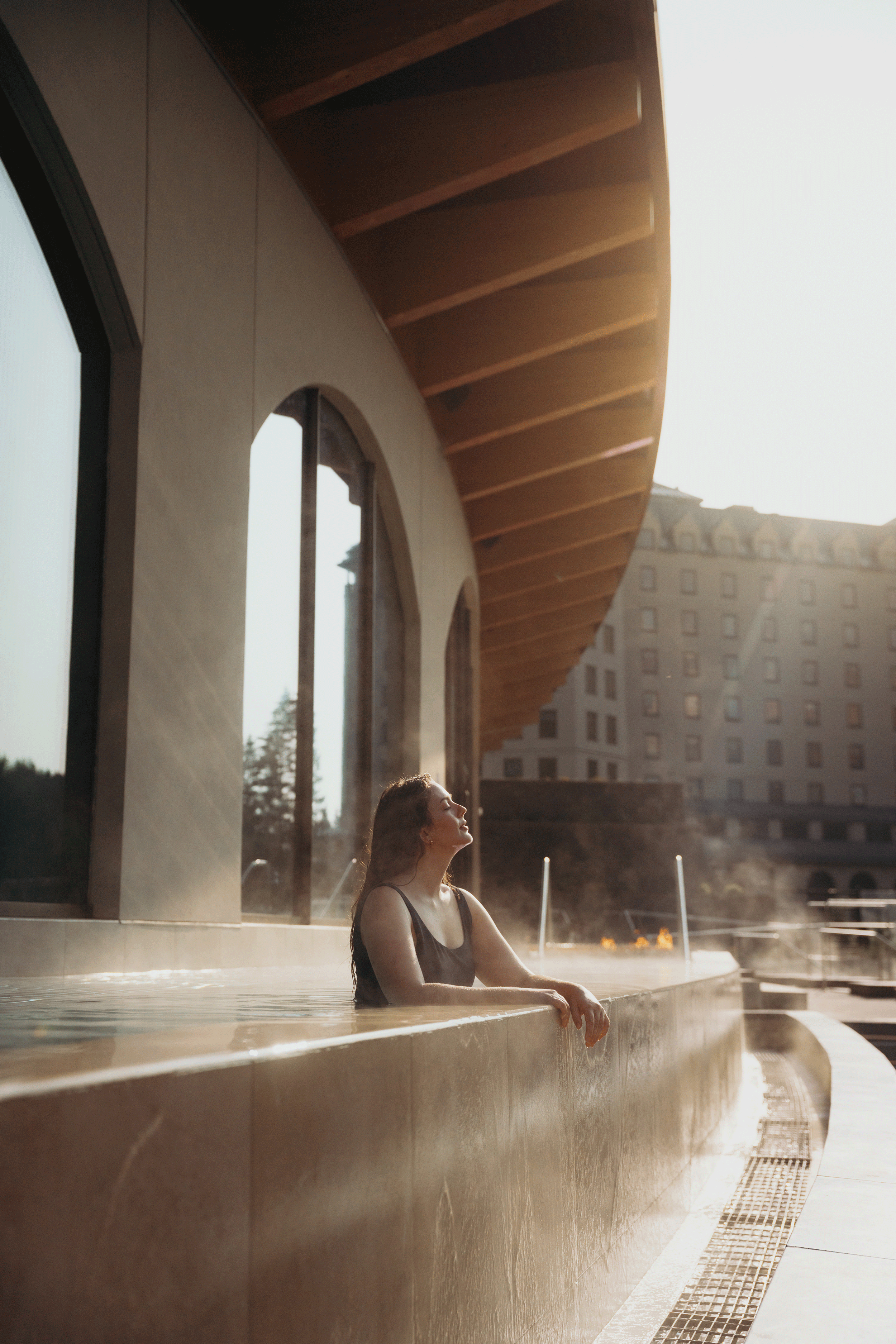 BASIN-Glacial-Waters---Vitality-Pool---Calin-&-Cate-Charles Women in the pool at BASIN with Fairmont Chateau Lake Louise in the background