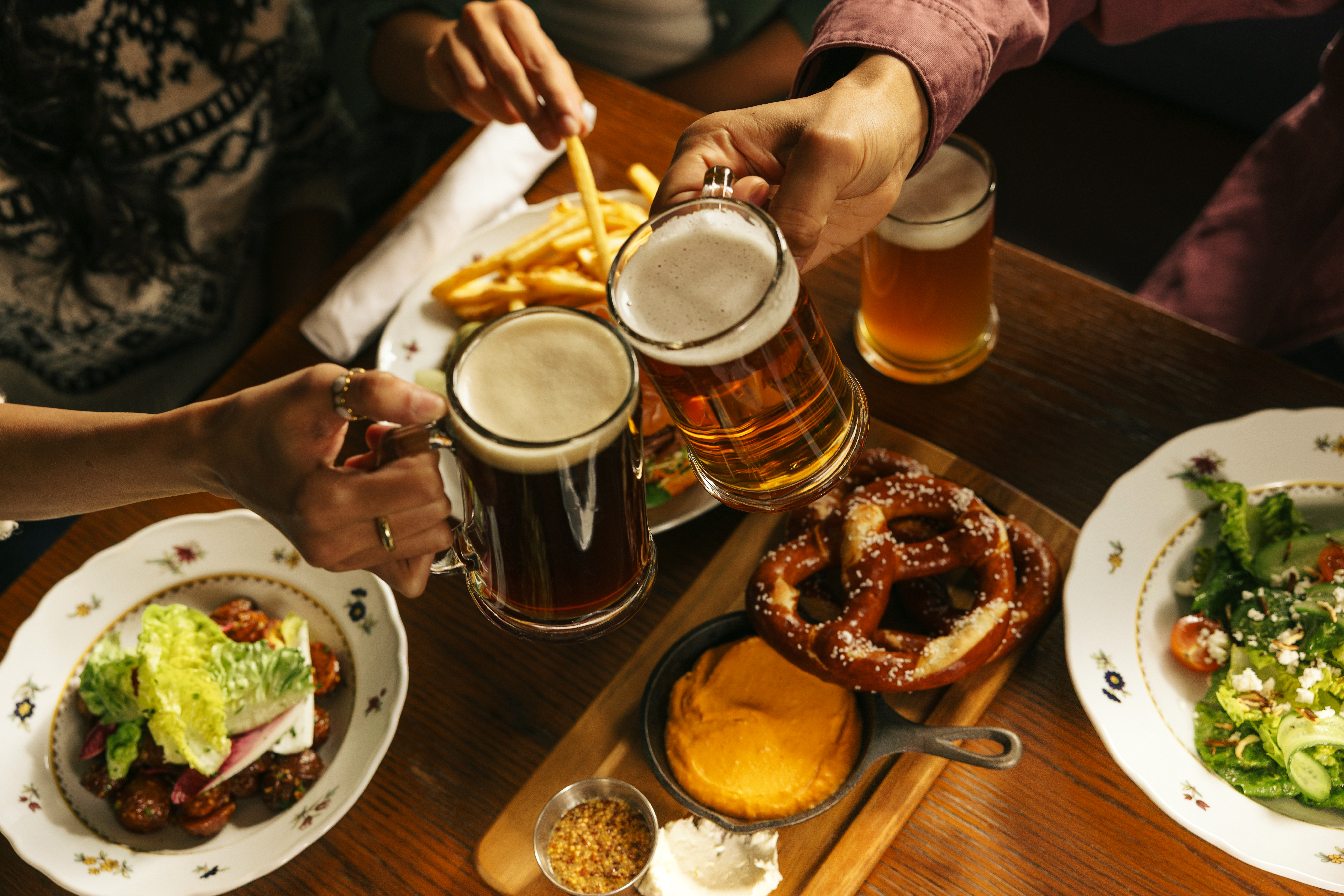 Dining table at Waldhaus Restaurant in Banff National Park set with beers, salad, pretzels and schnitzel.