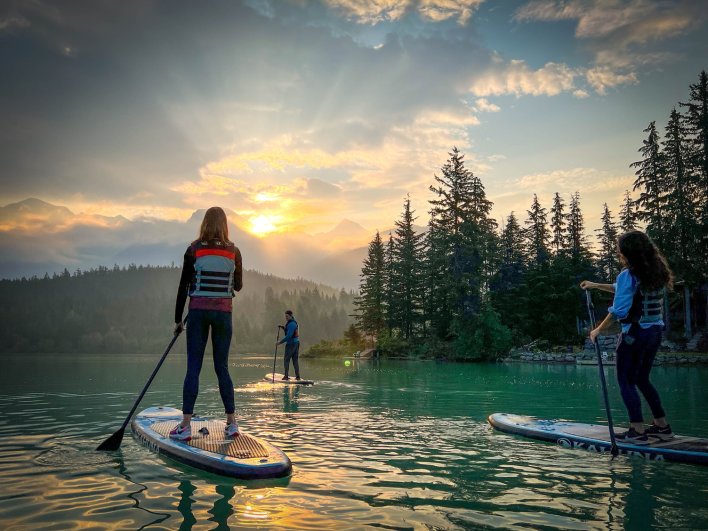 Paddleboarders enjoying the sunset on a lake in Whistler, Canada.