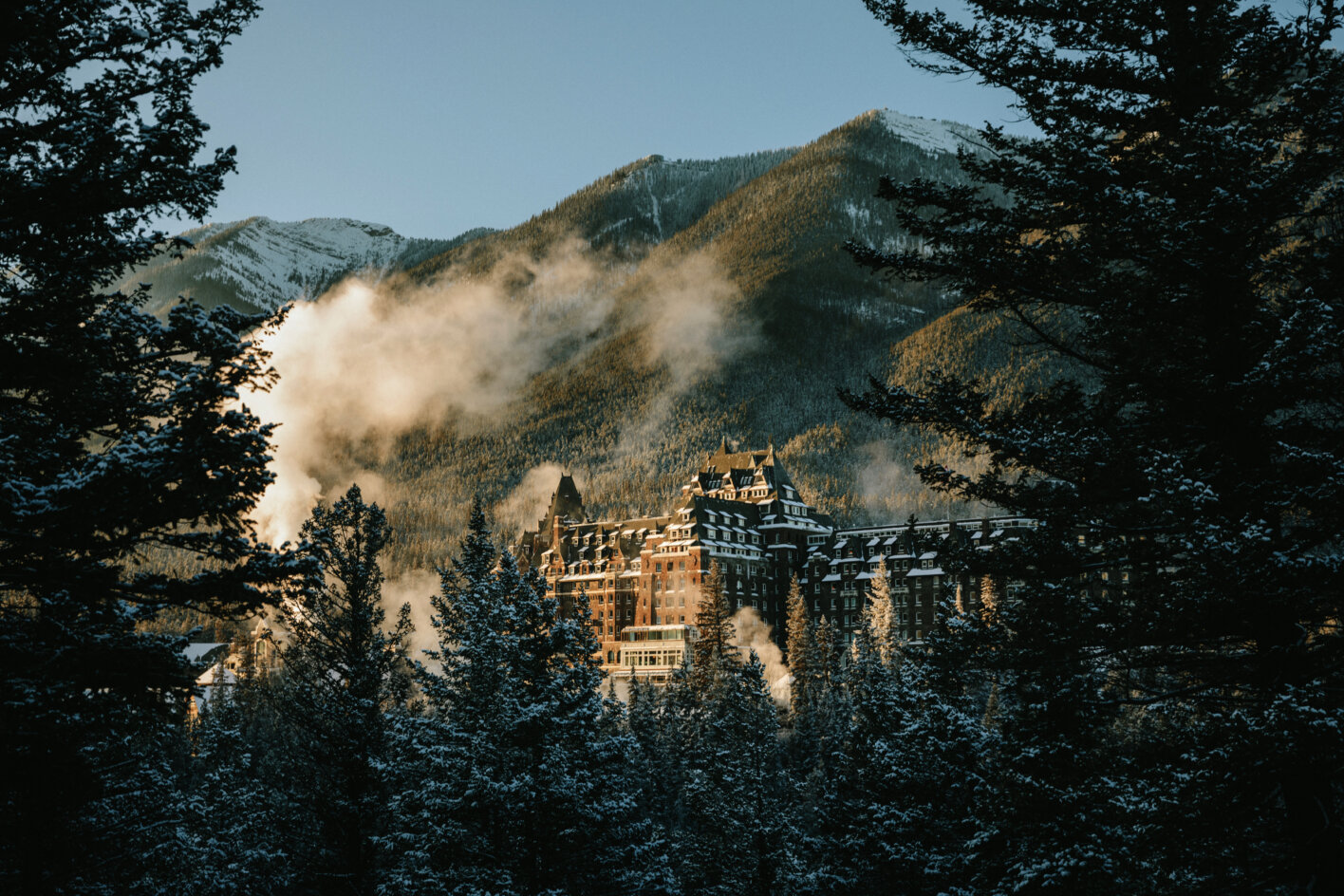 Fairmont Banff Springs surrounded by snow-covered forest and mountains in winter