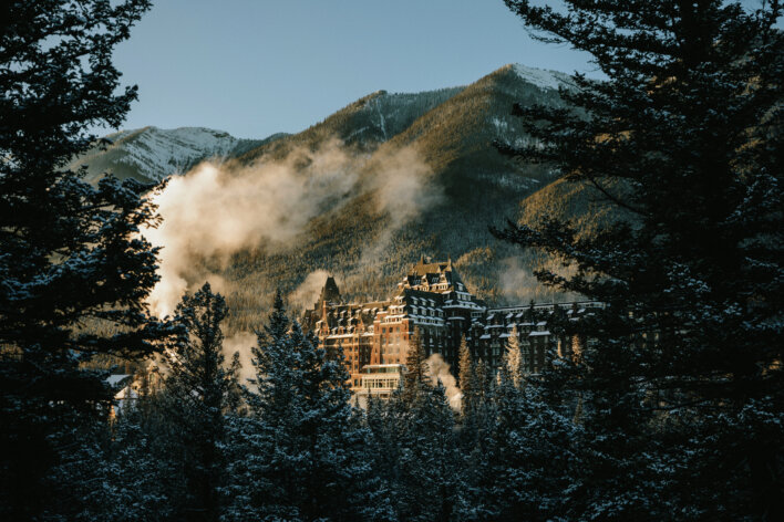 Fairmont Banff Springs surrounded by snow-covered forest and mountains in winter