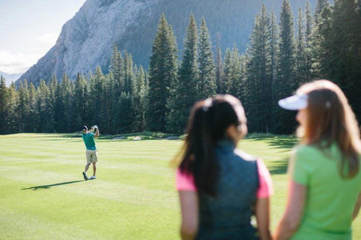 Golfers on Banff Springs course watching their friend hit off the fairway