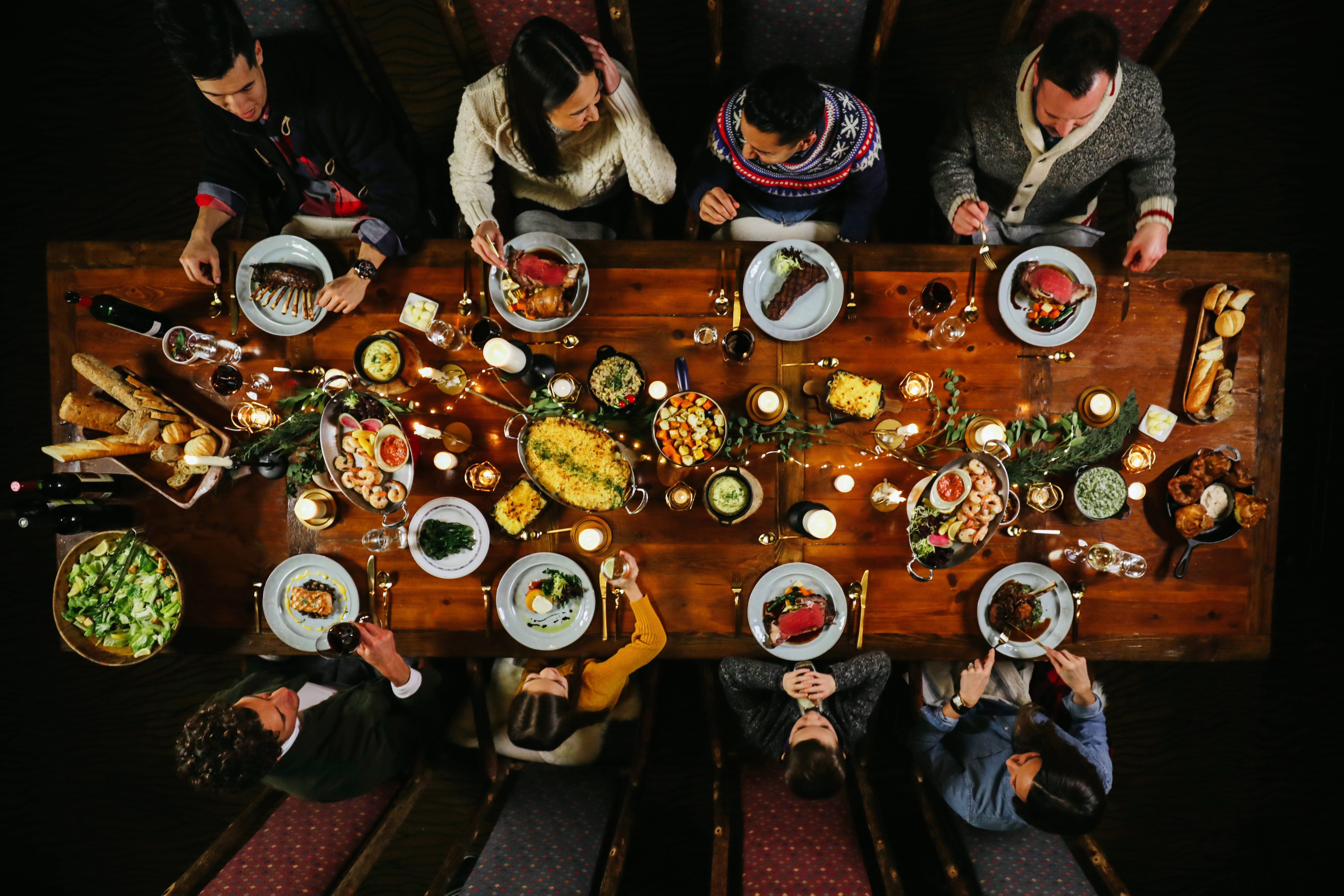 Group dining table filled with food and drinks and people.