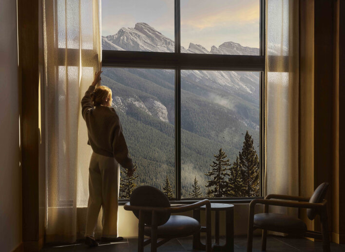 Woman looking rundle Mountain from floor to ceiling windows at Rimrock Banff, Emblems Collection