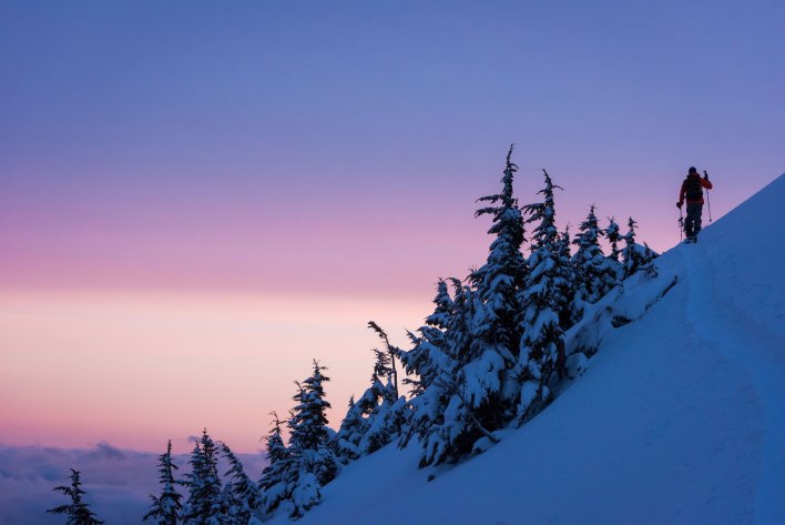 A person walking along the ridge while out on a split board tour in Whistler British Columbia.