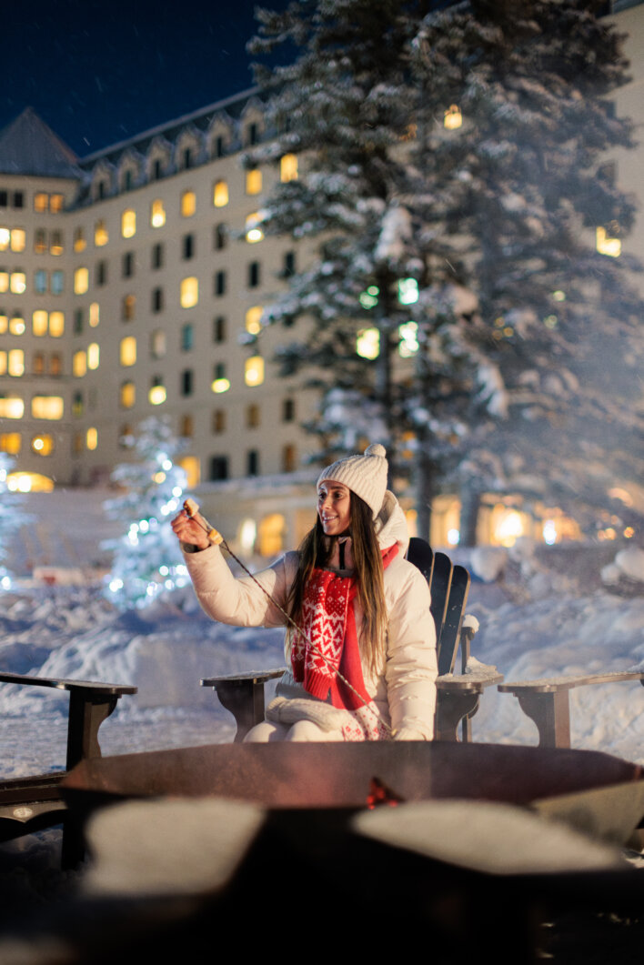 Guest roasting a marshmallow beside an outdoor fire at Fairmont Chateau Lake Louise